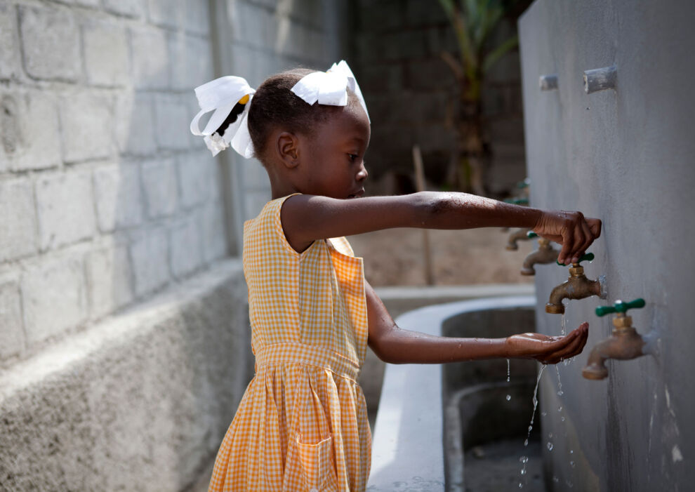 Tyttö pesee käsiään UNICEFin tuella rakennetussa käsienpesupisteessä koulussaan Port-au-Princessä, Haitilla. © UNICEF/UNI121139/Dormino