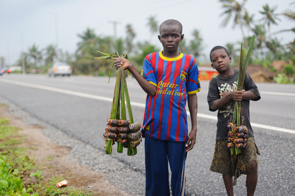 Ghanalaispojat Asiko ja Ishael myyvät rapuja tien varressa. Pojat eivät käy koulua, vaikka haluaisivat. © UNICEF/UNI198332/Quarmyne