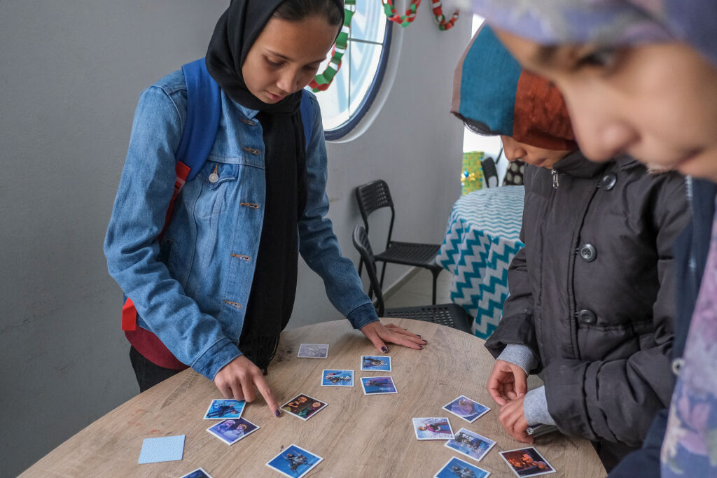 Lapset pelaavat Frozen-korteilla tilassa, jonka ovat järjestäneet UNICEF ja sen kumppanijärjestö Better Days. TAPUAT-niminen lapsi- ja perhekeskus sijaitsee Lesvoksen saarella Kreikassa. Lapset asuvat vastaaanotto- ja tunnistuskeskuksessa Moriassa. © UNICEF/UN0274821/Haviv VII Photo