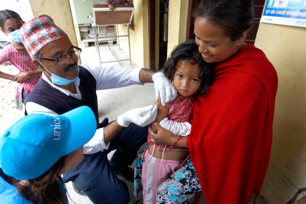 Neljävuotias Neisha Shakya saa tuhkarokko- ja vihurirokkorokotuksen Bungamatin terveysasemalla Kathmandun laaksossa. Neishan äiti Indu Maharjan toi tyttärensä terveysasemalle kuultuaan rokotuksista. Perhe asuu tilapäisessä telttakylässä.