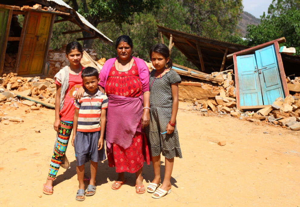 Shree Kalikan yläkoulun rehtori Rita Pyakhurel seisoo oppilaidensa Shanti Pyakhurelin, Sanjog Chalisen ja Samikshya Chalisen kanssa maanjäristyksessä tuhoutuneen koulun edessä Nuwakotissa Nepalissa. Ritan mukaan oppilaat kyselevät jatkuvasti, milloin he pääsevät takaisin kouluun. © UNICEF/Nepal 2015/Panday