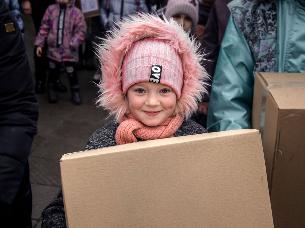 Ukrainalainen tyttö pitää käsissään UNICEFin avustuspakettia, jossa on talvivaatteita.