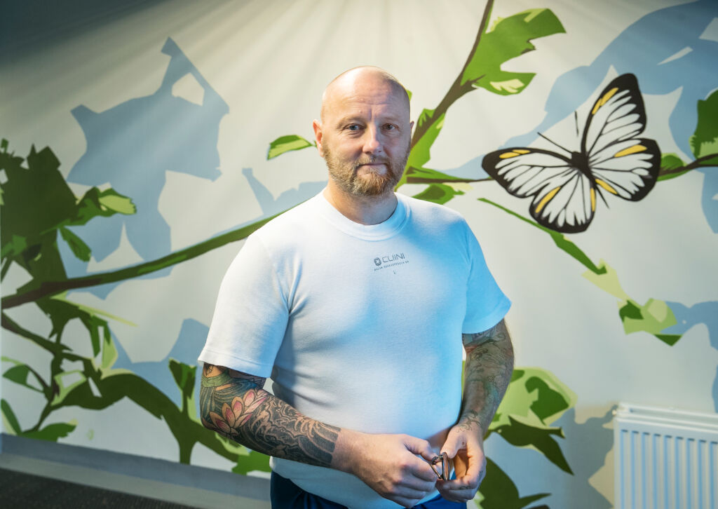 Valkoiseen t-paitaan pukeutunut henkilö katsoo kameraan.