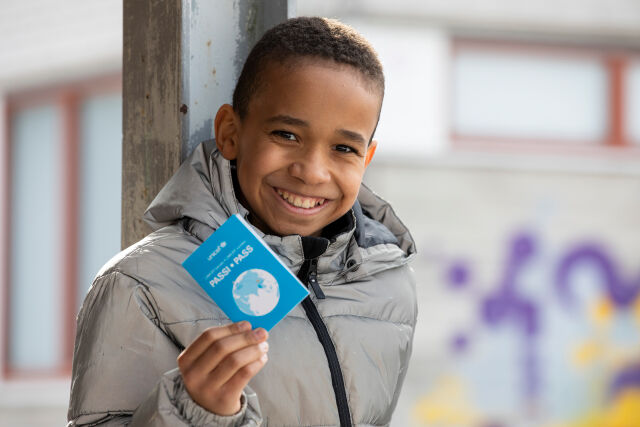 Koululainen näyttää UNICEF-kävelypassiaan.