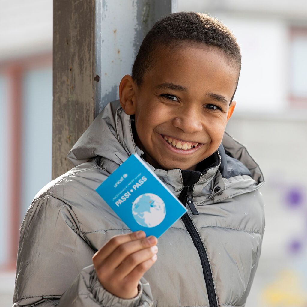 Lapsi esittelee UNICEF-kävelyn passia.