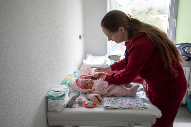 Äiti pukee vastasyntynyttä lasta pyödän ääressä sairaalassa.