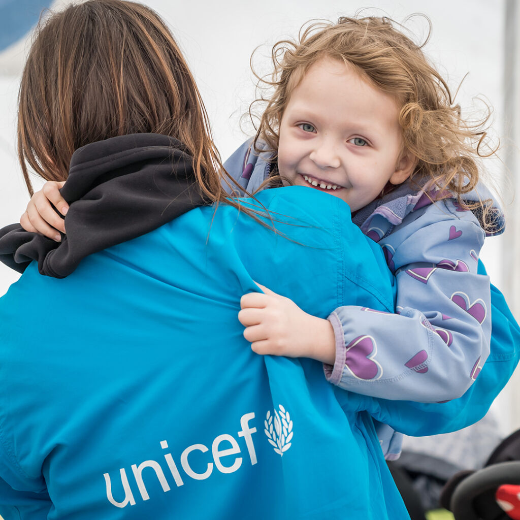 En UNICEF-anställd bär på ett leende barn.