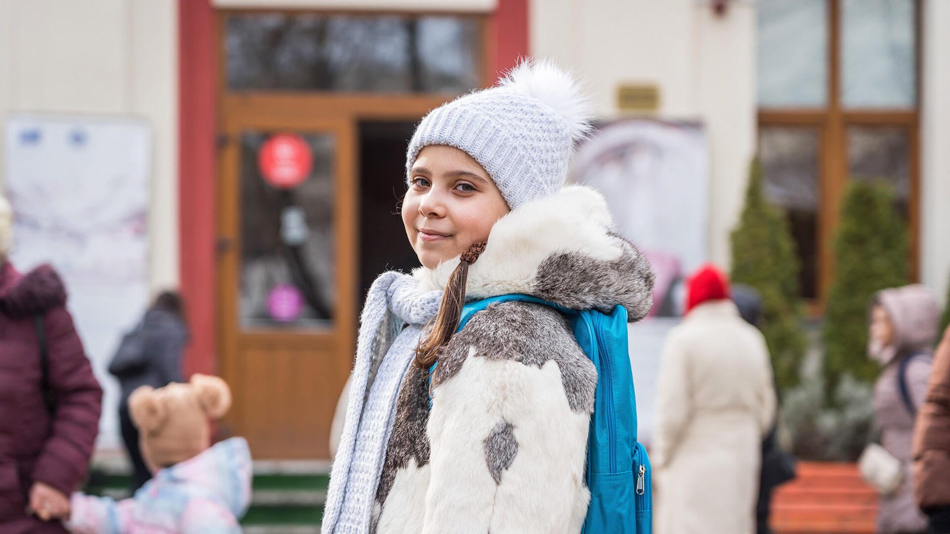 ukrainalaislapsi hymyilee koulune edessä UNICEFin koulureppu selässään